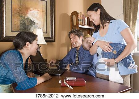 Family looking at laptop computer at home View Large Photo Image Stock Image - Family looking at laptop computer at home. Fotosearch