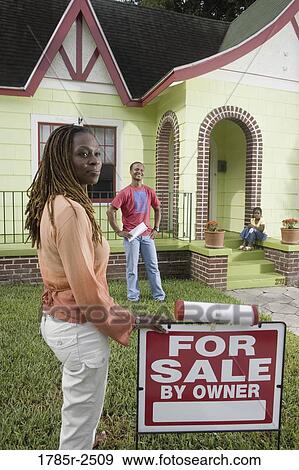 Family outside house with woman standing by "For Sale" sign View Large Photo Image Stock Photo - Family outside house with woman standing by "For Sale" sign. Fotosearch