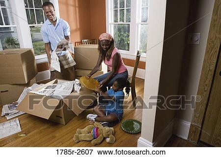 Stock Photo - Family packing or unpacking belongings from box. Fotosearch