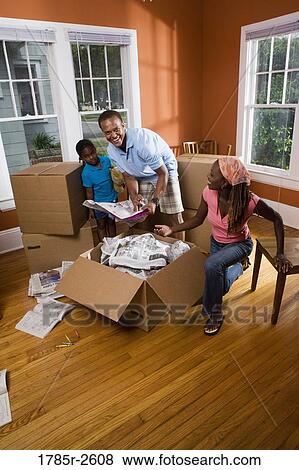 Family packing or unpacking belongings from box View Large Photo Image Stock Photo - Family packing or unpacking belongings from box. Fotosearch