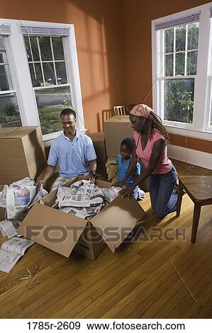 Family packing or unpacking belongings from box View Large Photo Image Stock Photo - Family packing or unpacking belongings from box. Fotosearch