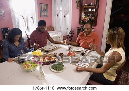 Family saying grace at dining table View Large Photo Image Stock Image - Family saying grace at dining table. Fotosearch
