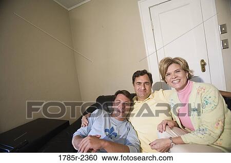 Family sitting on a sofa and smiling View Large Photo Image Stock Image - Family sitting on a sofa and smiling. Fotosearch