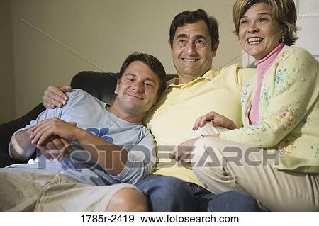 Family sitting on a sofa and smiling View Large Photo Image Stock Photo - Family sitting on a sofa and smiling. Fotosearch