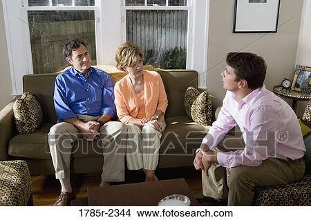 Family sitting on a sofa at home, conversing View Large Photo Image Picture - Family sitting on a sofa at home, conversing. Fotosearch
