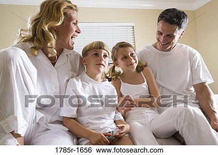 Family sitting on foot of bed in pajamas View Large Photo Image Stock Photograph - Family sitting on foot of bed in pajamas. Fotosearch