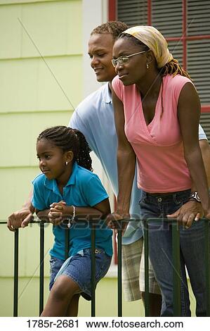 Family standing by a railing outside a house View Large Photo Image Stock Image - Family standing by a railing outside a house. Fotosearch