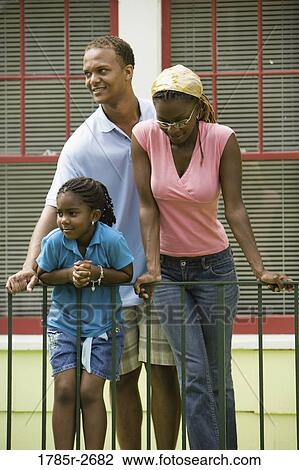 Family standing by a railing outside a house View Large Photo Image Stock Image - Family standing by a railing outside a house. Fotosearch