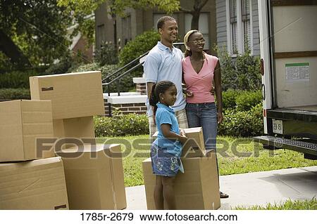 Family standing by boxes next to moving truck View Large Photo Image Stock Photo - Family standing by boxes next to moving truck. Fotosearch