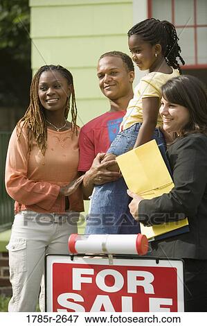 Family standing outside a house with a real estate broker View Large Photo Image Stock Photo - Family standing outside a house with a real estate broker. Fotosearch