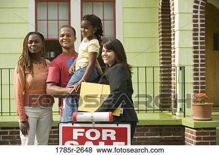 Family standing outside a house with a real estate broker View Large Photo Image Stock Photo - Family standing outside a house with a real estate broker. Fotosearch