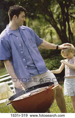 Stock Photo - Father and daughter standing beside a barbeque grill. Fotosearch