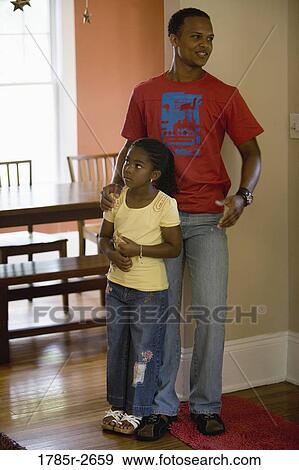 Stock Photo - Father and daughter standing inside a house. Fotosearch