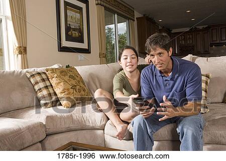 Father and daughter watching TV and fighting over the remote control View Large Photo Image Stock Photograph - Father and daughter watching TV and fighting over the remote control. Fotosearch