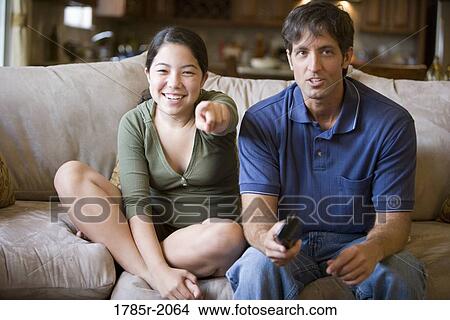 Father and daughter watching TV from sofa View Large Photo Image Picture - Father and daughter watching TV from sofa. Fotosearch