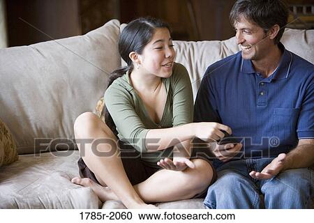 Father and daughter watching TV from sofa View Large Photo Image Stock Image - Father and daughter watching TV from sofa. Fotosearch