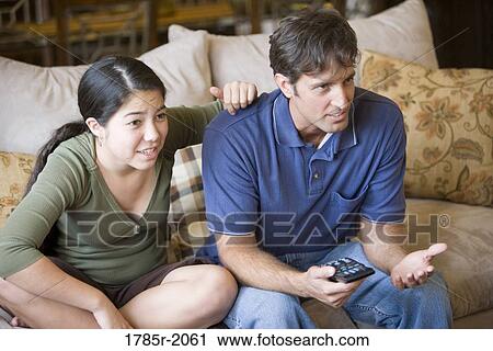 Father and daughter watching TV from sofa View Large Photo Image Stock Image - Father and daughter watching TV from sofa. Fotosearch