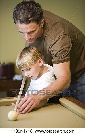 Stock Photo - Father showing his young son how to shoot pool. Fotosearch