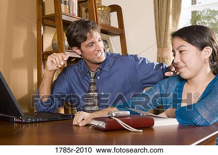 Father using laptop computer at home while his teenage daughter watches View Large Photo Image Stock Image - Father using laptop computer at home while his teenage daughter watches. Fotosearch
