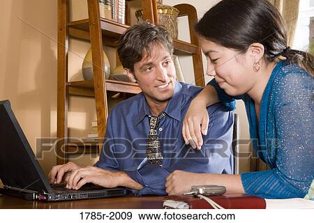 Father using laptop computer at home while his teenage daughter watches View Large Photo Image Stock Photo - Father using laptop computer at home while his teenage daughter watches. Fotosearch