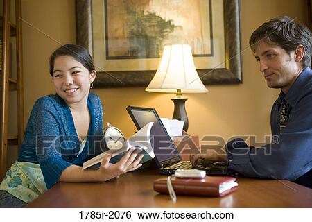 Father using laptop computer at home while his teenage daughter reads a book View Large Photo Image Stock Photograph - Father using laptop computer at home while his teenage daughter reads a book. Fotosearch