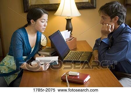 Father using laptop computer at home while his teenage daughter reads a book View Large Photo Image Stock Photography - Father using laptop computer at home while his teenage daughter reads a book. Fotosearch
