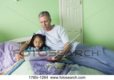 Father with daughter reading book in bedroom View Large Photo Image Picture - Father with daughter reading book in bedroom. Fotosearch