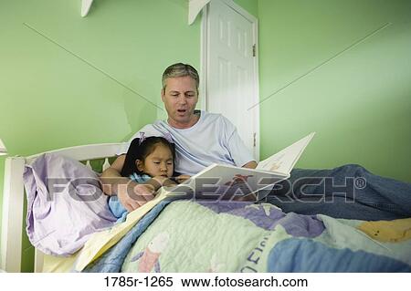 Stock Photography - Father with daughter reading book in bedroom. Fotosearch