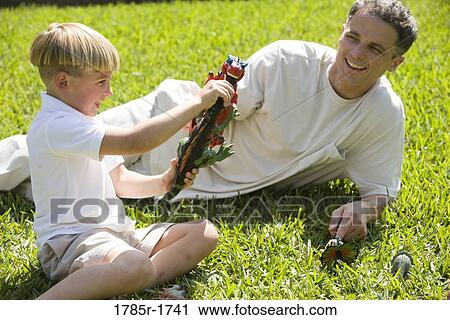 Father with son playing with toy dinosaurs on grassy lawn View Large Photo Image Stock Image - Father with son playing with toy dinosaurs on grassy lawn. Fotosearch
