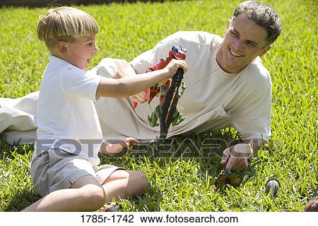 Father with son playing with toy dinosaurs on grassy lawn View Large Photo Image Stock Image - Father with son playing with toy dinosaurs on grassy lawn. Fotosearch