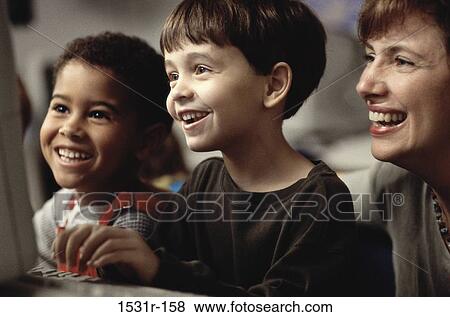 Female teacher in front of a computer monitor with two boys View Large Photo Image Stock Photo - Female teacher in front of a computer monitor with two boys. Fotosearch