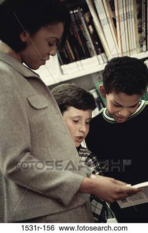 Female teacher reading a book with two students View Large Photo Image Stock Photograph - Female teacher reading a book with two students. Fotosearch
