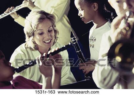 Female teacher teaching students how to play the flute View Large Photo Image Stock Image - Female teacher teaching students how to play the flute. Fotosearch