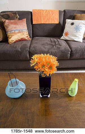 Flowers in vase arranged on coffee table with pillows on sofa in background View Large Photo Image Stock Photo - Flowers in vase arranged on coffee table with pillows on sofa in background. Fotosearch