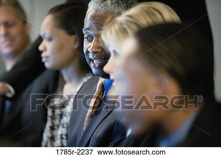 Stock Photo - Focus on African American business man in group meeting. Fotosearch