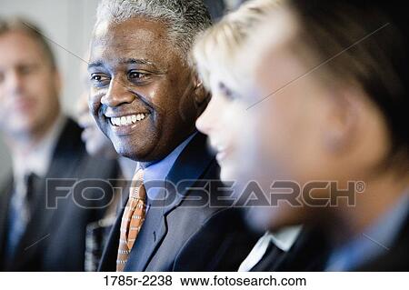 Stock Photo - Focus on African American business man in group meeting. Fotosearch