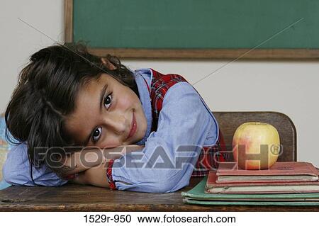 Stock Image - Girl laying her head on a desk in a classroom. Fotosearch