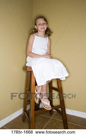 Stock Photo - Girl sitting in corner on stool. Fotosearch