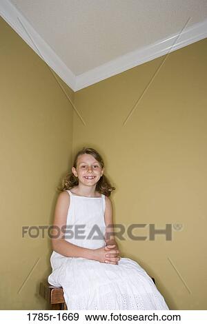 Stock Photo - Girl sitting in corner on stool. Fotosearch