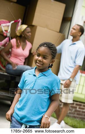 Stock Photography - Girl smiling with parents in background. Fotosearch