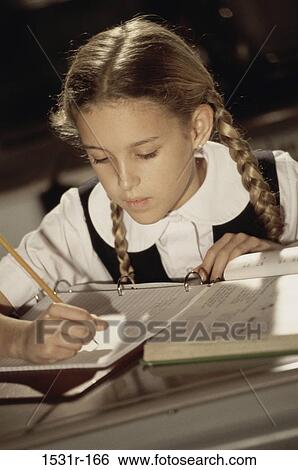 Stock Photograph - Girl writing in a book with a pencil. Fotosearch
