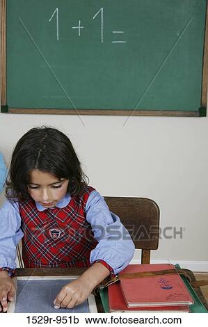 Girl writing on a chalkboard in a classroom View Large Photo Image Stock Image - Girl writing on a chalkboard in a classroom. Fotosearch