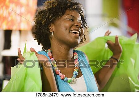 Happy young woman in a boutique carrying shopping bags View Large Photo Image Stock Photo - Happy young woman in a boutique carrying shopping bags. Fotosearch