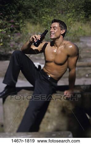 Stock Photo - High angle view of a man drinking a bottle of beer outdoors. Fotosearch