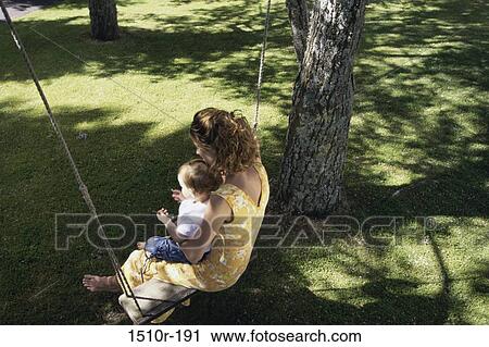 High angle view of a mother sitting on a swing with her baby boy View Large Photo Image Stock Image - High angle view of a mother sitting on a swing with her baby boy. Fotosearch