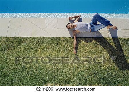 High angle view of a young man lying at the poolside View Large Photo Image Stock Photograph - High angle view of a young man lying at the poolside. Fotosearch