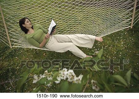 High angle view of a young woman lying in a hammock reading a book View Large Photo Image Stock Image - High angle view of a young woman lying in a hammock reading a book. Fotosearch