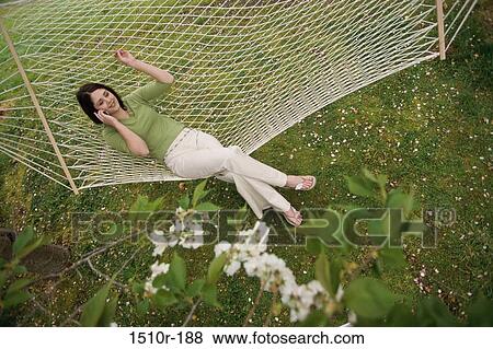 Stock Photo - High angle view of a young woman lying in a hammock talking on a mobile phone. Fotosearch
