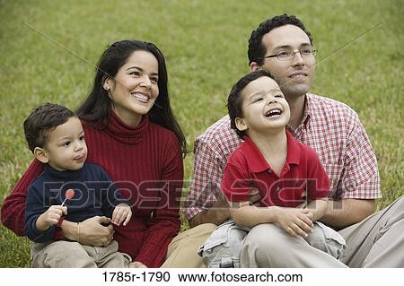 Stock Image - Hispanic family sitting on grass. Fotosearch