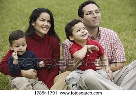 Stock Image - Hispanic family sitting on grass. Fotosearch